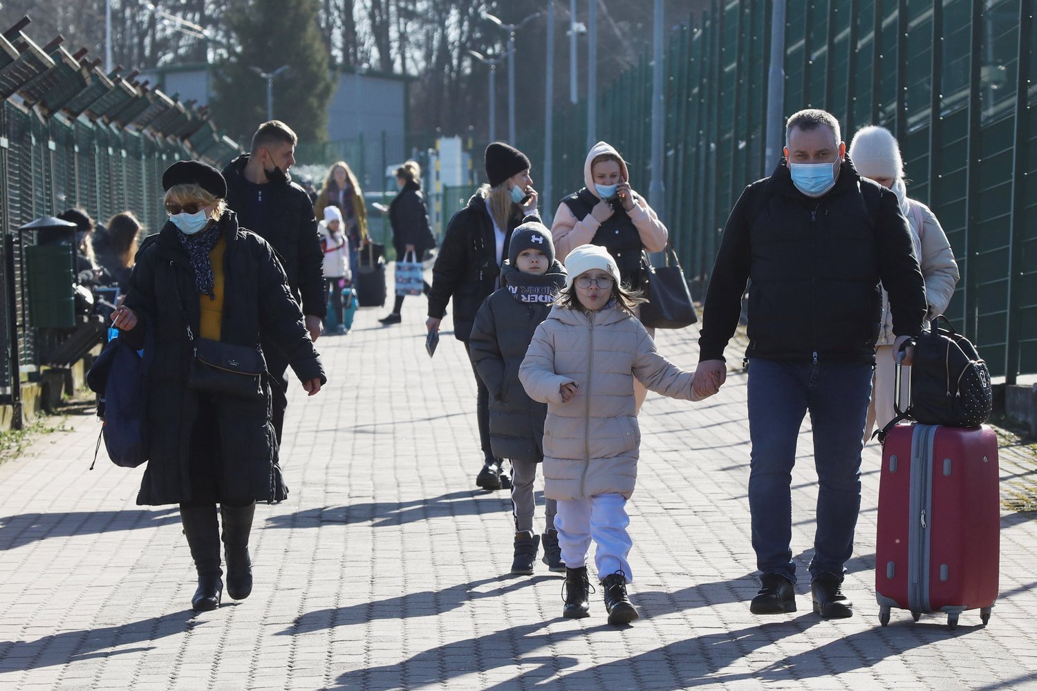 A family carry their belongings walk at the border crossing between Poland and Ukraine in Medyka, Poland, Feb. 24, 2022, after Russian President Vladimir Putin authorized a military operation in eastern Ukraine.