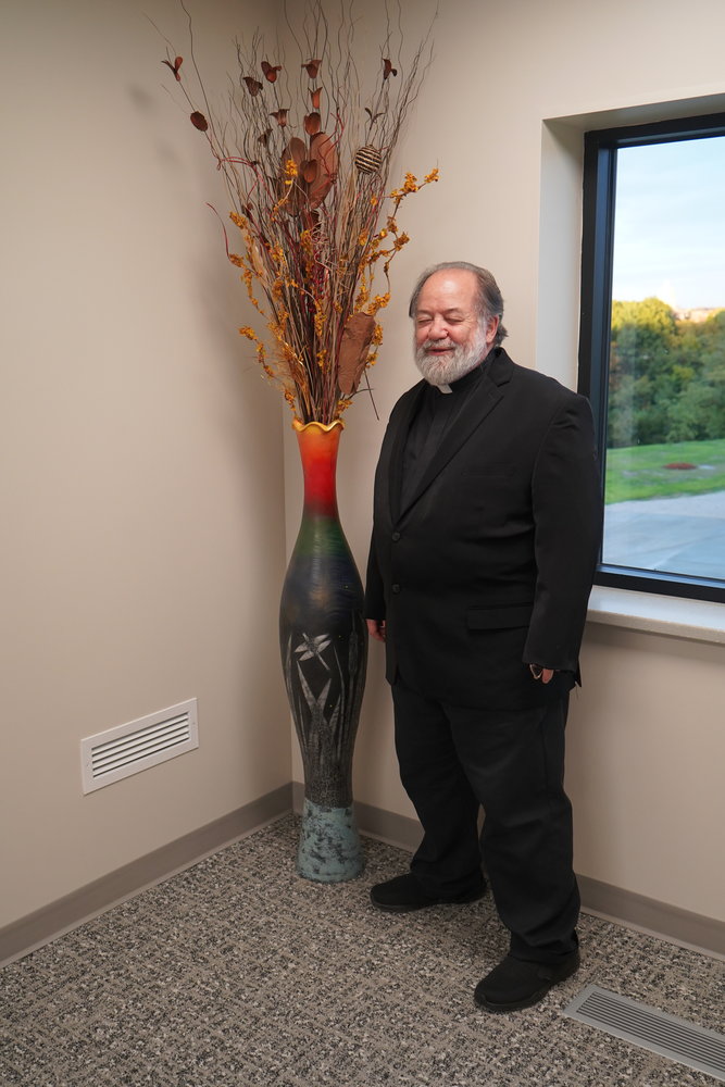 Father David Means stands next to a wood-turning sculpture he created for the Catholic Charities Center in Jefferson City.