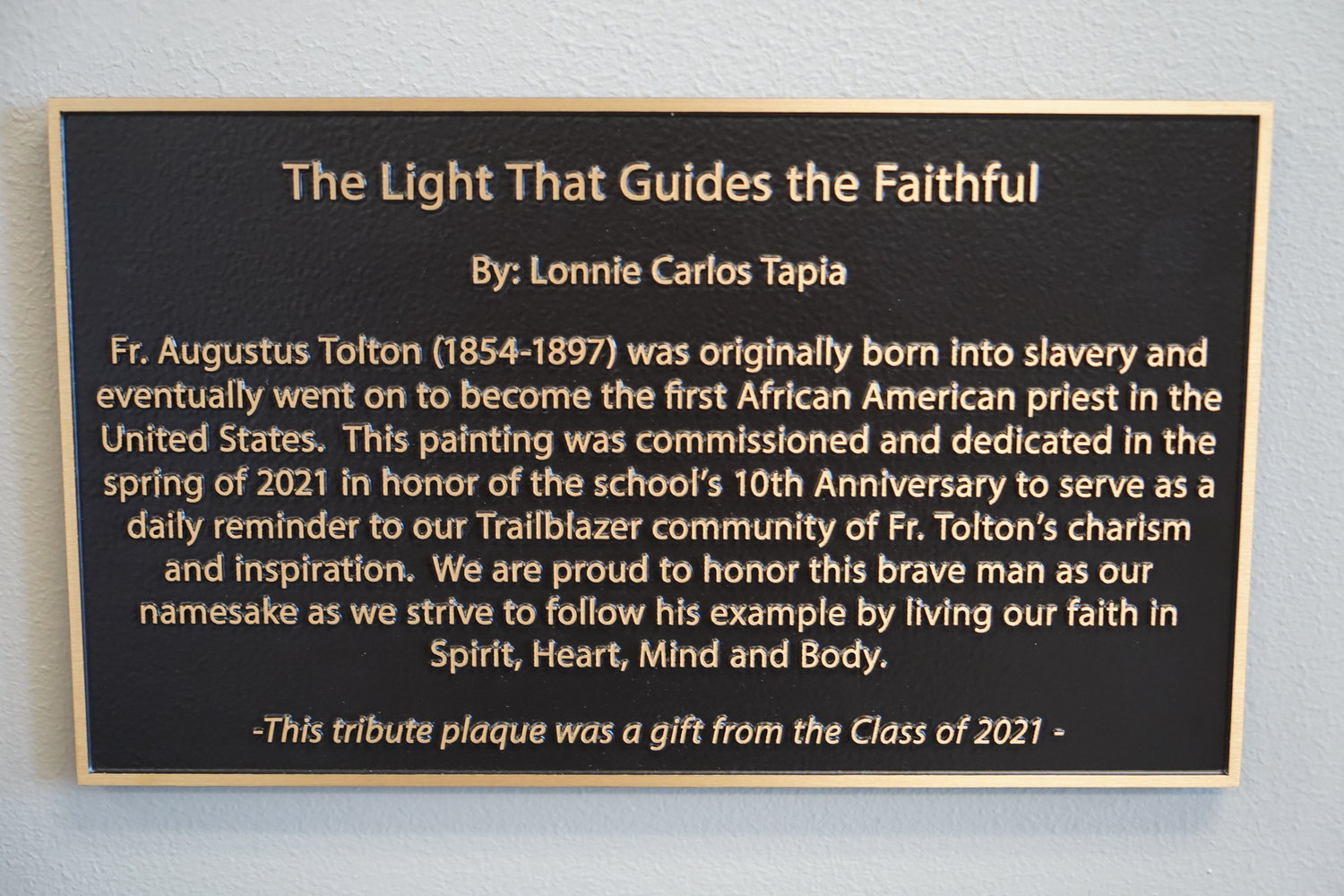 The school’s Class of 2021 donated the plaque beside the painting, which hangs in a busy area next to the chapel of the school building.