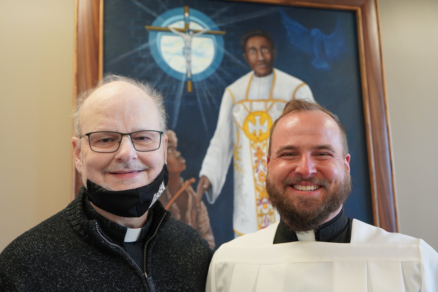 Father Mike Coleman and Father Paul Clark, chaplains at Fr. Tolton Regional Catholic High School, stand near the newly unveiled artwork, "The Light that Guides the Faithful."